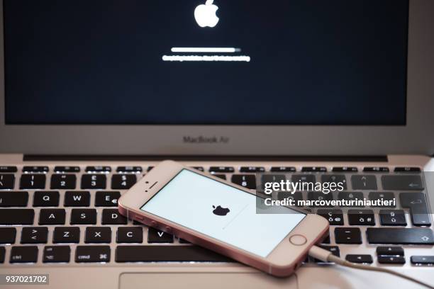 an iphone and a macbook are being updated - marcoventuriniautieri stock pictures, royalty-free photos & images