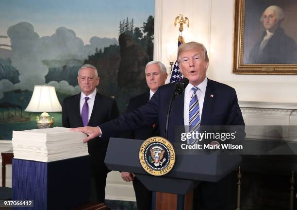 President Donald Trump gestures to the $1.3 trillion spending bill passed by Congress early Friday, with Vice President Mike Pence , and Defense...