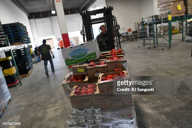 Tim Sanford, an employee at We Don't Waste, uses a forklift in the cooler to get pallets of food to be loaded onto trucks on March 23, 2018 in...