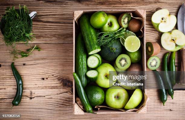 fresh sliced green vegetables and fruits in wooden crate - groenhout stockfoto's en -beelden