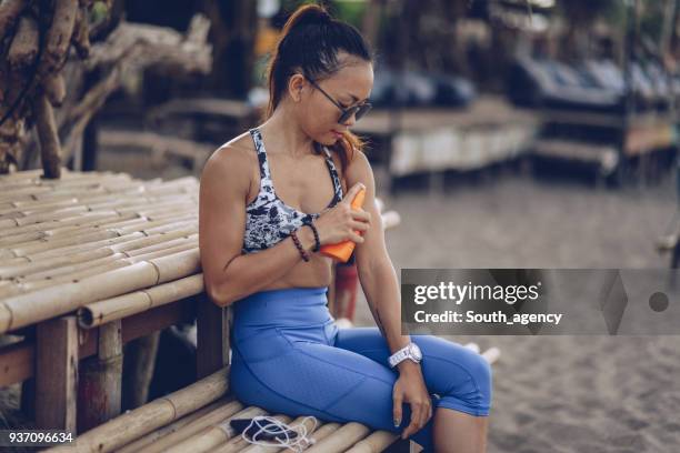 cute girl putting sun cream - legs crossed at knee slim stock pictures, royalty-free photos & images