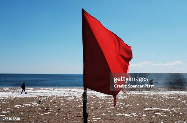 People walk along the beach at Coney Island on a spring afternoon on March 23, 2018 in New York City. Following weeks of cold, snow and ice, New...