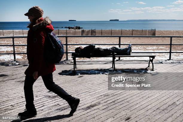 Man rests in the sun along the Coney Island boardwalk on a spring afternoon on March 23, 2018 in New York City. Following weeks of cold, snow and...