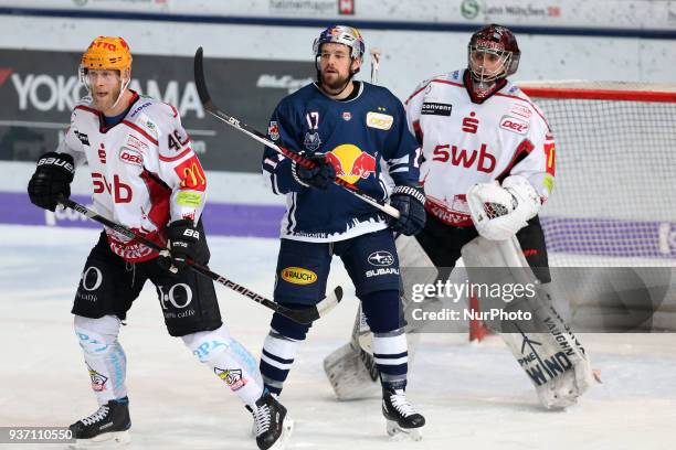 Nicholas B. Jensen of Pinguins Bremerhaven vies Brooks Macek of Red Bull Munich in front of Tomas Poepperle of Pinguins Bremerhaven during the DEL...