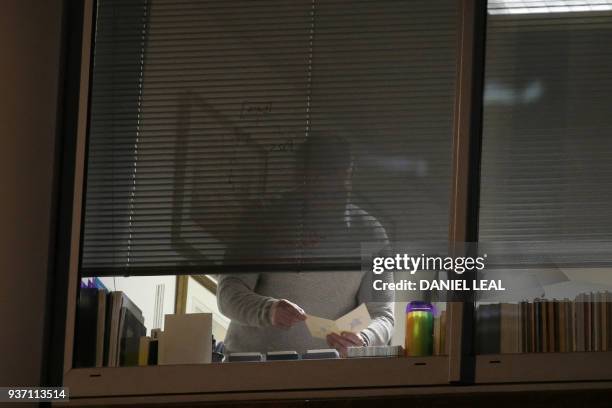 Man is pictured looking through papers inside the offices of Cambridge Analytica in central London on the evening of March 23 just hours after a...