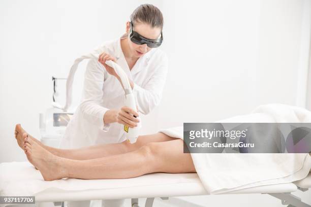 dermatologist removing hair with diode laser from patient's legs - hairy body woman stock pictures, royalty-free photos & images