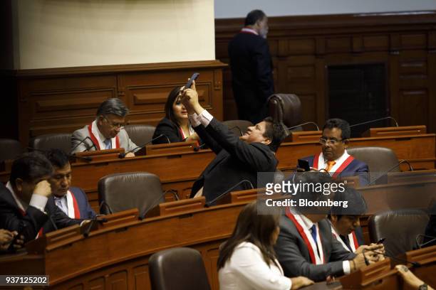 Member of congress uses a mobile device to take a 'selfie' photograph before Martin Vizcarra, Peru's president, center, is sworn into office during a...