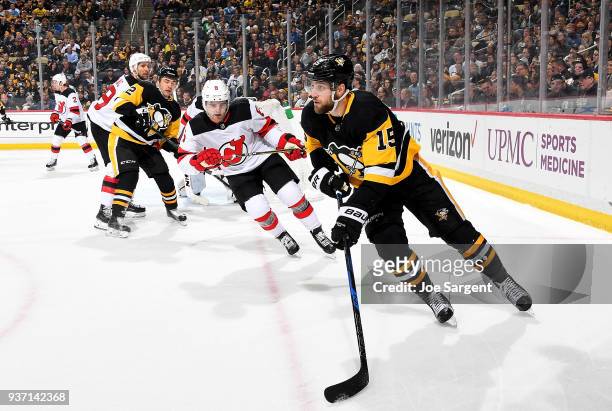 Riley Sheahan of the Pittsburgh Penguins handles the puck against Will Butcher of the New Jersey Devils at PPG Paints Arena on March 23, 2018 in...
