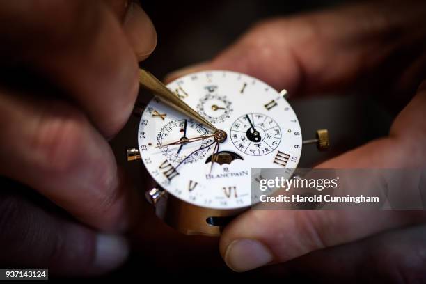 Watchmaker moves a watch hands on the Blancpain booth at the BaselWolrd watch fair on March 23, 2018 in Basel, Switzerland. The annual watch trade...