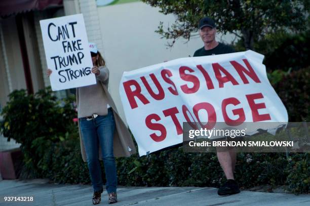 Protesters are seen as a motorcade with US President Donald Trump passes on its way to Mar-a-Lago Airport March 23, 2018 in Palm Beach, Florida. /...