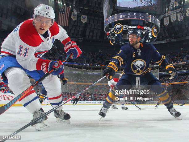 Marco Scandella of the Buffalo Sabres and Brendan Gallagher of the Montreal Canadiens reach for the puck along the boards during an NHL game on March...