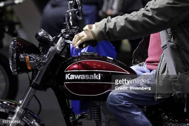 An attendee tries out a Kawasaki Heavy Industries Ltd. Estrella Final Edition motorcycle on display at the Tokyo Motorcycle Show in Tokyo, Japan, on...