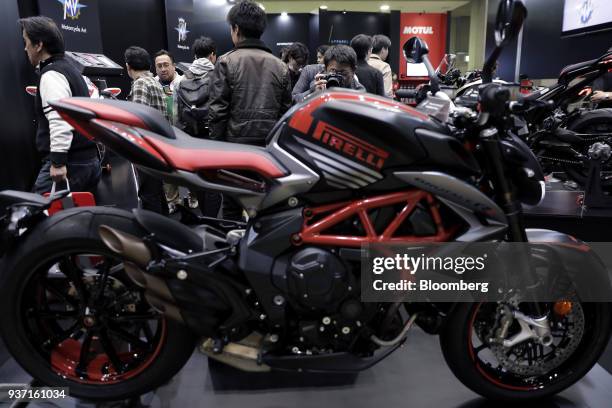 An attendee, top center, takes a photograph of an MV Agusta Motor SpA Brutale 800 RR Pirelli motorcycle on display at the Tokyo Motorcycle Show in...