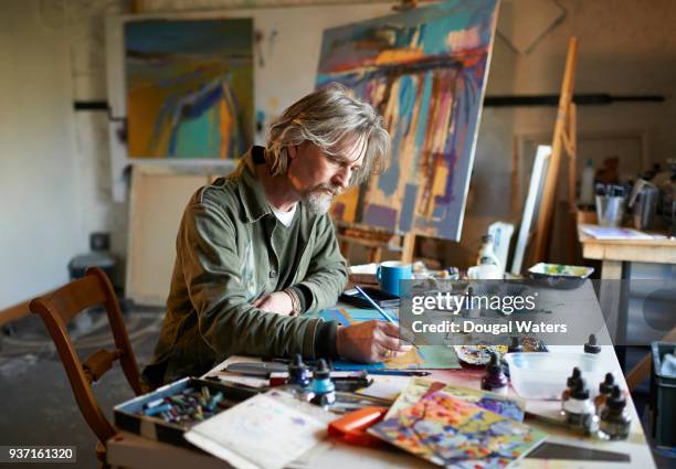 artist working on painting concentrating in studio. - male artist stock pictures, royalty-free photos & images