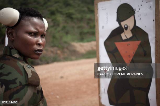 Central African Armed Forces soldier looks at her target during a training with an assault rifle at Camp Kassai, in Bangui, on March 14, 2018. At...