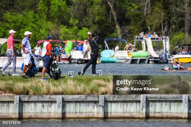 Patrick Reed hits a tee shot while fans on boats watch on the 14th hole during round three of the World Golf Championships-Dell Technologies Match...
