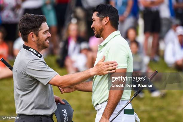 Louis Oosthuizen of South Africa shakes hands with Jason Day of Australia after winning their match 2-up on the 18th hole green during round three of...