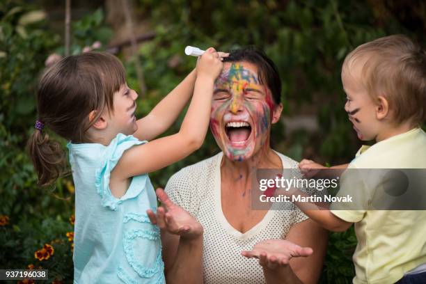 too much creativity - children painting mother's face - family drawing stock-fotos und bilder