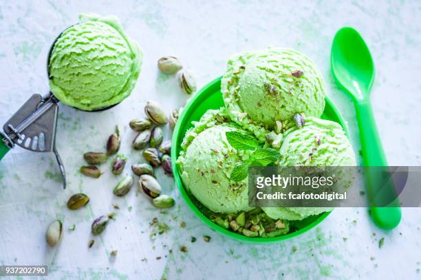 glace à la pistache dans un bol vert tiré sur table de jardin - glace pistache photos et images de collection