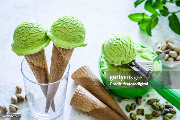 pistachio ice cream cones shot on garden table - pistachio ice cream stock pictures, royalty-free photos & images