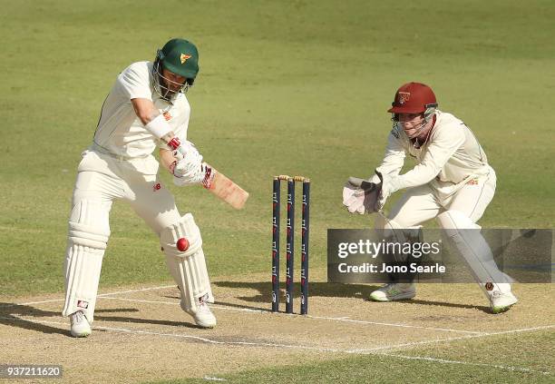 Matthew Wade of Tasmania plays a shot as Queensland wicket keeper Jimmy Peirson looks on during day two of the Sheffield Shield Final match between...