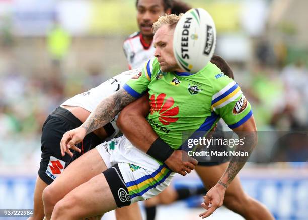 Blake Austin of the Raiders is tackled after passing during the round three NRL match between the Canberra Raiders and the New Zealand Warriors at...