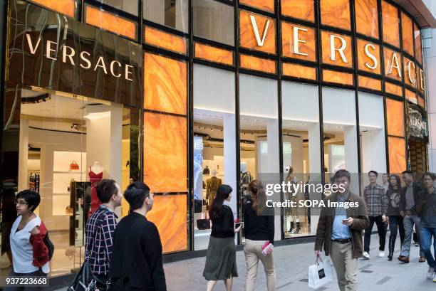 Pedestrians walks past the Italian luxury fashion company Versace in Queen's Road, Central district, Hong Kong.