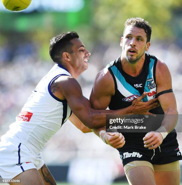 Travis Boak captain of Port Adelaide handballs under pressure from Danyle Pearce of the Dockers during the round one AFL match between the Port...