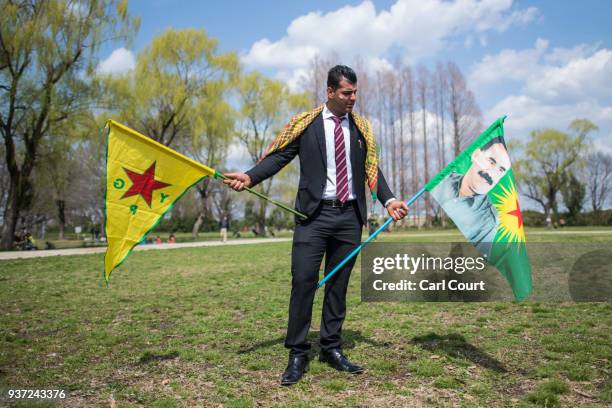 Kurdish man holds a flag of the Kurdish People's Protection Units and another bearing a picture of Abdullah Ocalan, the founder and leader of the...