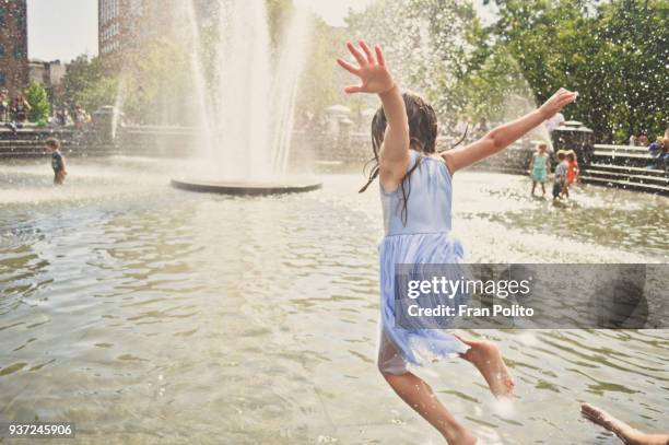 a girl jumping into the water at a city fountain. - fuente estructura creada por el hombre fotografías e imágenes de stock