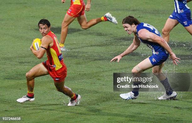 Lachie Weller of the Suns looks to get away from Ben Brown of the Kangaroos during the round one AFL match between the Gold Coast Suns and the North...