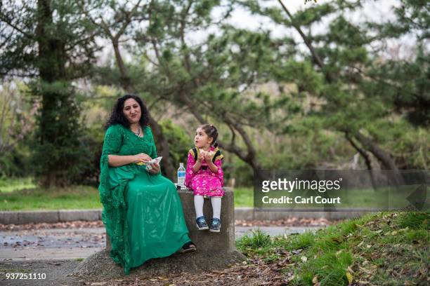 Kurdish woman in traditional dress sits with a young girl as they eat during Nowruz celebrations on March 24, 2018 in Tokyo, Japan. Nowruz meaning...