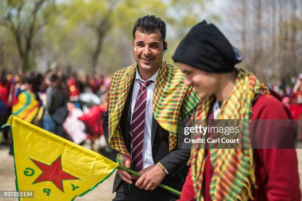 Kurdish man holds a flag of the Kurdish People's Protection Units as he talks with a friend during Nowruz celebrations on March 24, 2018 in Tokyo,...