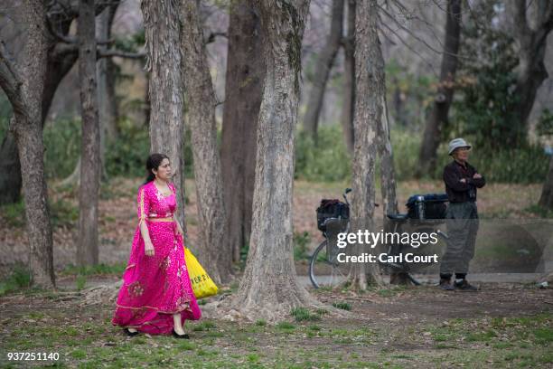 Kurdish woman in traditional dress passes a Japanese man as she walks to her friends during Nowruz celebrations on March 24, 2018 in Tokyo, Japan....