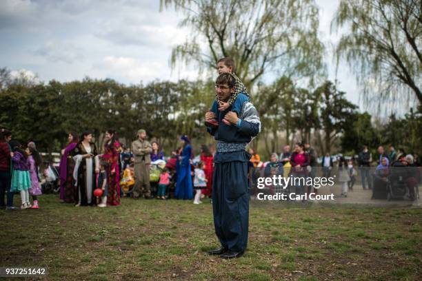 Kurdish man in traditional attire carries a child on his shoulders as he looks on during Nowruz celebrations on March 24, 2018 in Tokyo, Japan....