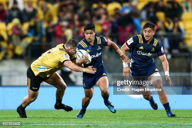 Josh Ioane of the Highlanders is tackled by Fraser Armstrong of the Hurricanes while Marino Mikaele-Tu'u looks on during the round six Super Rugby...