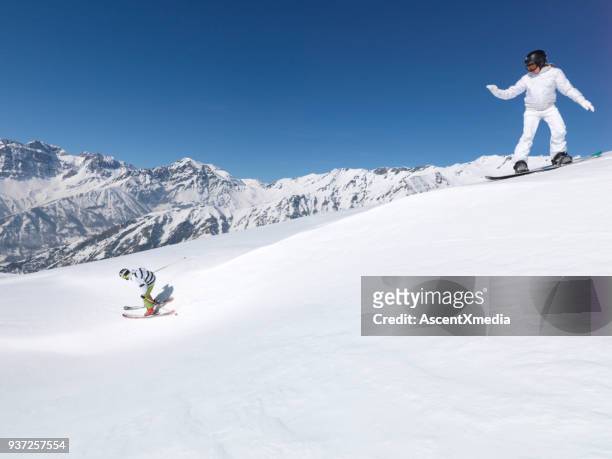 weibliche snowboard folgt männlichen skifahrer berg hinunter - confidence male landscape stock-fotos und bilder