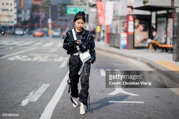 Guest wearing black vinyl jacket, white bag, black pants, white ankle boots is seen at the Hera Seoul Fashion Week 2018 F/W at Dongdaemun Design...