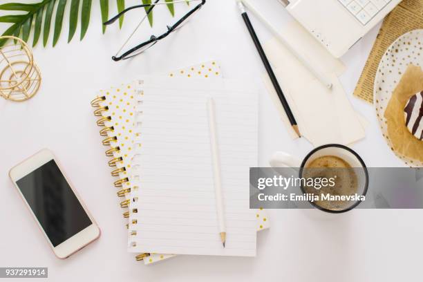 desk view with a blank notepad, open laptop, coffee and donuts - notepad table stockfoto's en -beelden