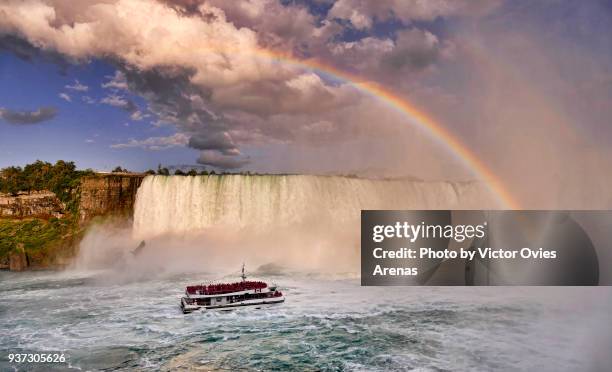 rainbow over the american side of the horseshoe falls and boat with tourists, niagara falls, new york, usa - niagara falls rainbow stock pictures, royalty-free photos & images