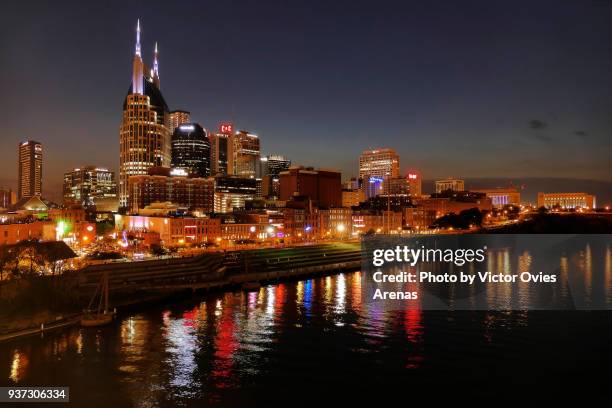 nasville skyline and reflection on the river cumberland from john seigenthaler pedestrian bridge lit at twilight, nashville, tennessee, usa - nashville night stock pictures, royalty-free photos & images