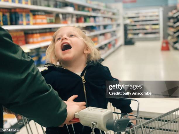 child sat in a shopping trolley at the supermarket - supermarket trolley female stock-fotos und bilder