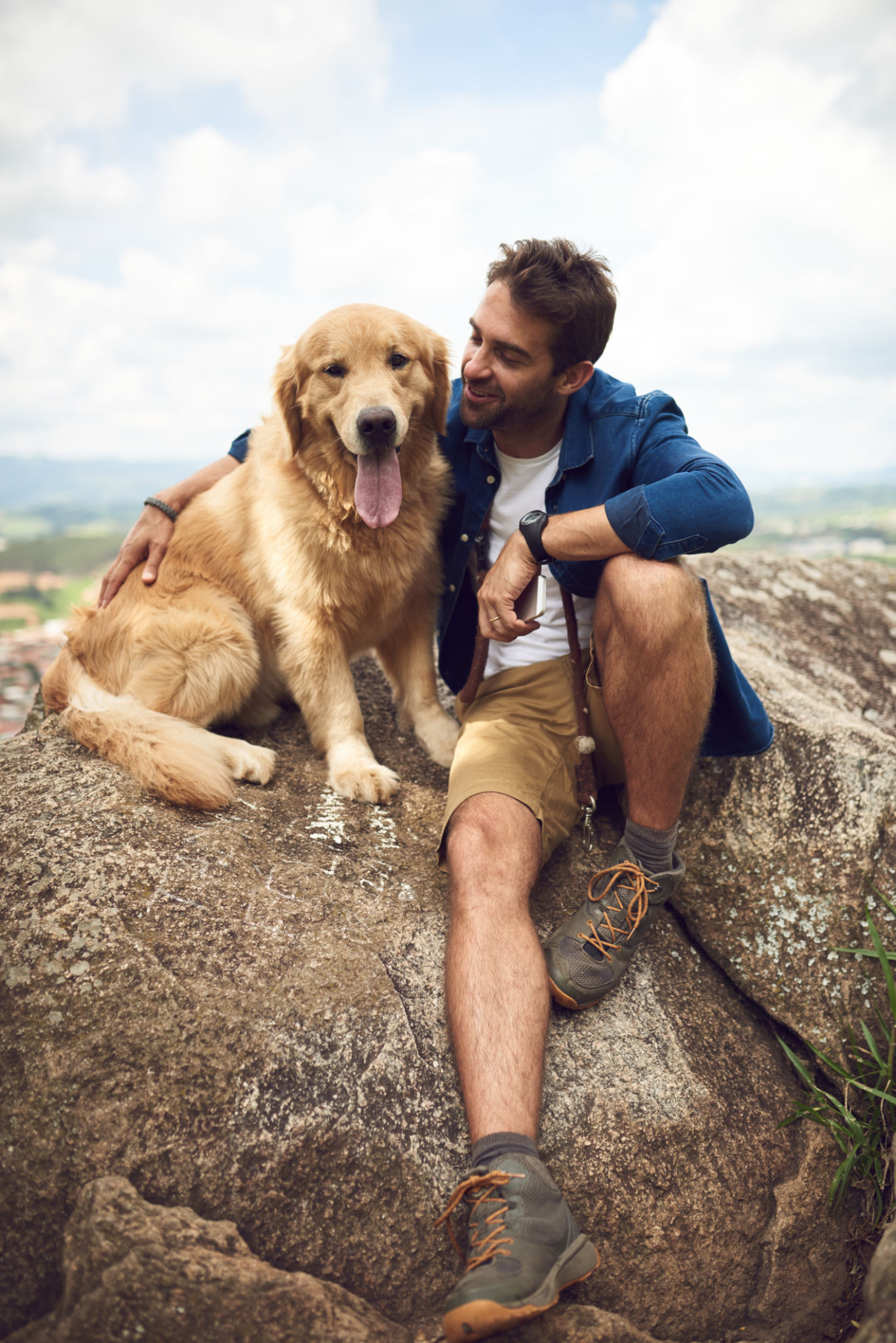 A man sitting on a rock, with his Golden Retriever A man sitting on a rock, with his Golden Retriever
