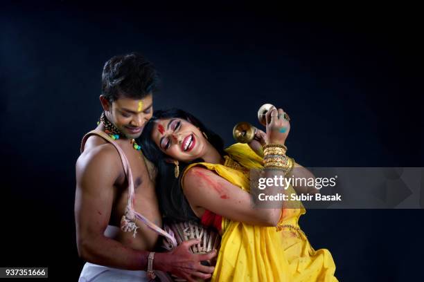 couple celebrating holi with colors and traditional musical instruments. - subir basak stockfoto's en -beelden