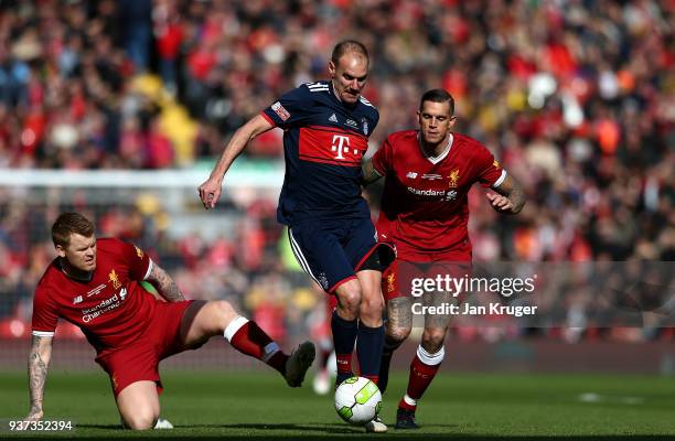 Alexander Zickler of Bayern Munich Legends skips over the tackle of John Arne Riise and Daniel Agger of Liverpool Legends during the friendly match...