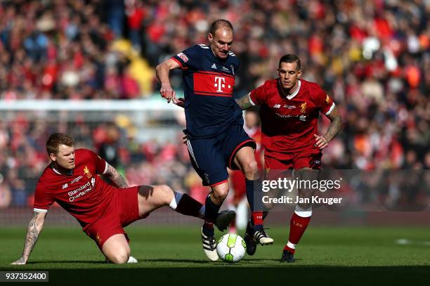 Alexander Zickler of Bayern Munich Legends skips over the tackle of John Arne Riise and Daniel Agger of Liverpool Legends during the friendly match...