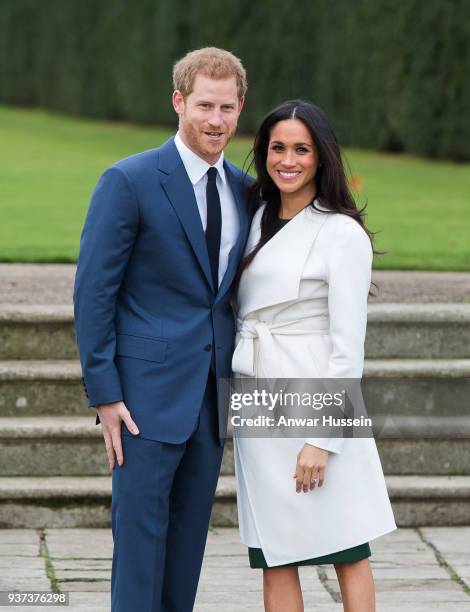 Prince Harry and Meghan Markle, wearing a white belted coat by Canadian brand Line The Label, attend a photocall in the Sunken Gardens at Kensington...