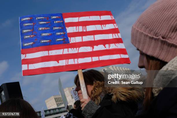 Woman holds a sign with an American flag dripping red and its stars replaced by bullets while protesting at the "March for our Lives" gathering on...