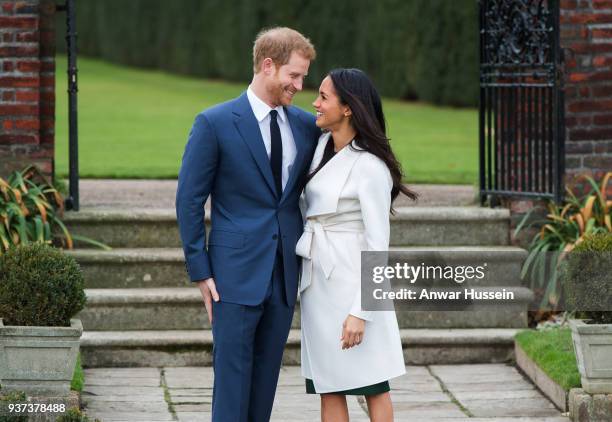 Prince Harry and Meghan Markle, wearing a white belted coat by Canadian brand Line The Label, attend a photocall in the Sunken Gardens at Kensington...