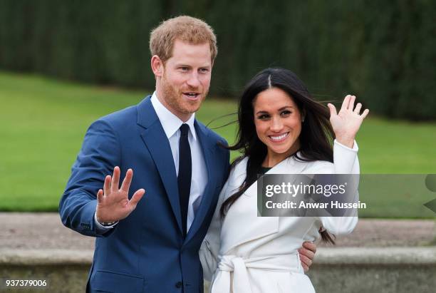 Prince Harry and Meghan Markle, wearing a white belted coat by Canadian brand Line The Label, attend a photocall in the Sunken Gardens at Kensington...